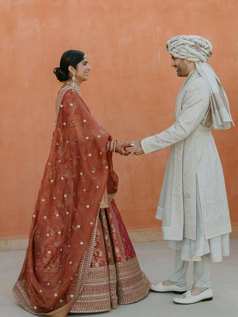Indian wedding in Oberoi Marrakech. The couple standing infront of the walls of oberoi, holding hands.